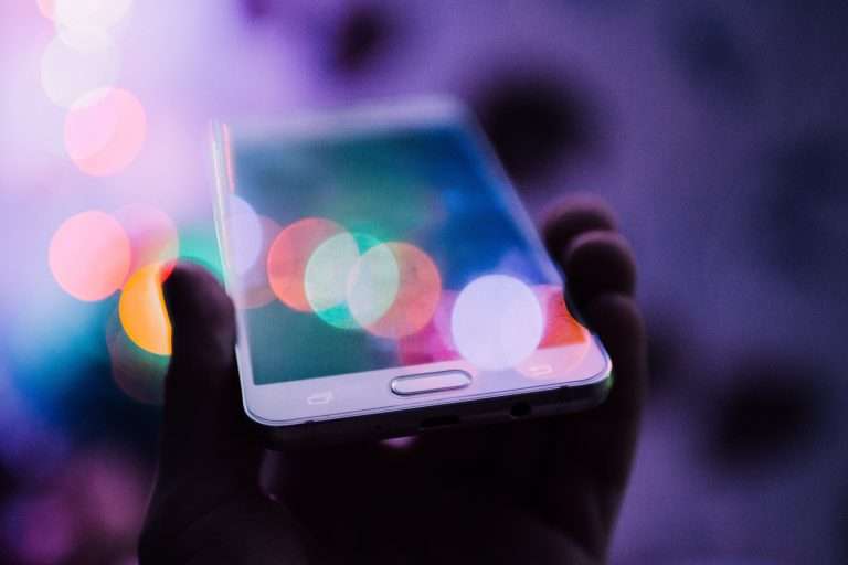 Smartphone in hand with multicolor lights reflected
