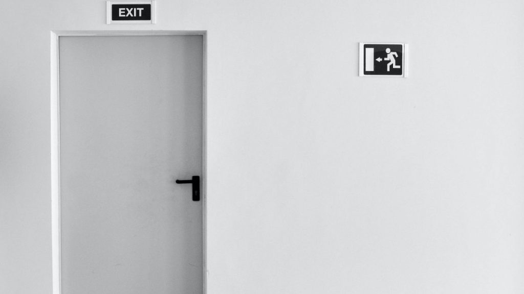 White wall and door with a black color emergency exit sign