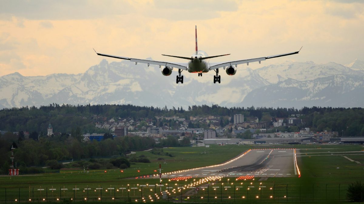 Airplane making its landing with a scenic mountainous background.