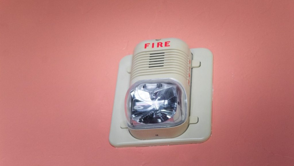 White fire alarm on a pink wall